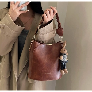 Detail of vintage brown bucket bag with woven handle and cute rabbit plush charm