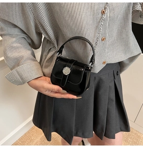 Detail of mini black patent leather crossbody bag with silver C-buckle and chain strap