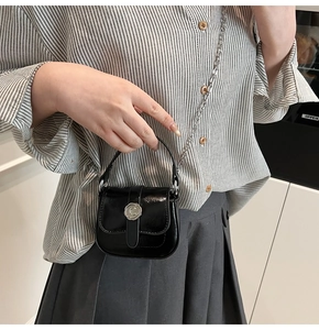 Detail of a mini black glossy shoulder bag with silver C-logo clasp and chain strap