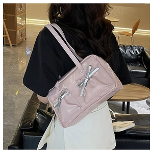 Detail of pink glossy shoulder bag featuring silver bows and elegant double straps