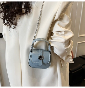 Detail of light blue mini flap bag with golden chain strap and round metal buckle detail