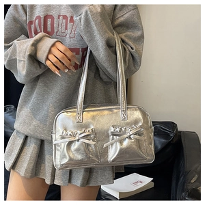 Detail view of the silver metallic tote bag featuring side pockets and bow decorations