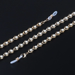 Chaîne de lunettes élégante en métal doré avec perles blanches sur fond noir élégant