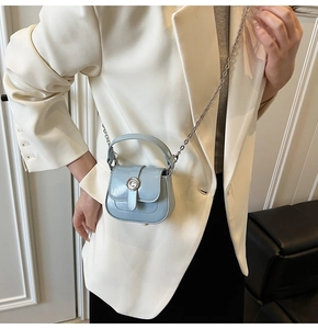 Detail of light blue mini leather crossbody bag with silver buckle worn on a white suit