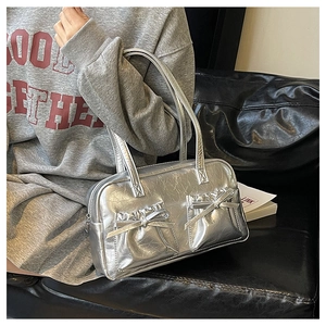 Close-up of silver Y2K bow Boston bag with metallic finish and double front pockets