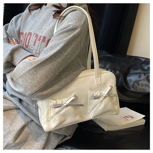Detail of creamy white boston bag featuring front pockets and silver ribbon bows
