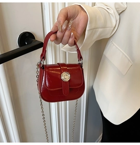 Detail of red patent leather mini bag featuring silver C-shaped clasp and metal chain