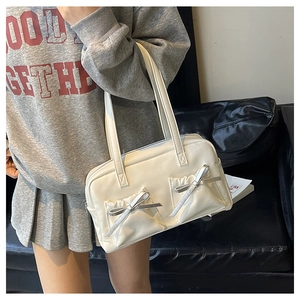 Detail of cream white tote bag featuring decorative bows and pleated front pockets