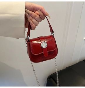 Close-up of red mini crossbody bag with glossy finish and elegant pearl chain strap
