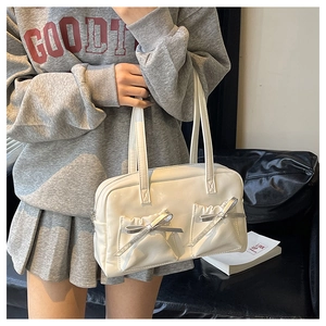 Close-up of white glossy tote bag with dual bows and pockets in a lifestyle setting