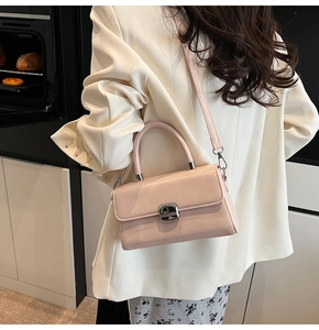 Sac bandoulière rose rectangulaire avec boucle argentée porté dans un intérieur moderne