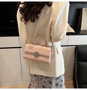 Détail d'un mini sac carré rose brillant porté à l'épaule avec fermoir rotatif argenté