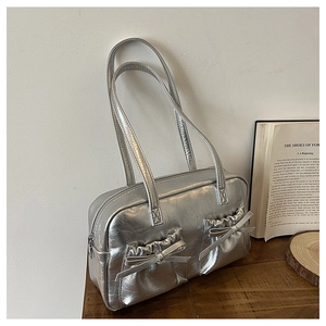 Detail of silver metallic shoulder bag featuring wrinkled texture and decorative bows