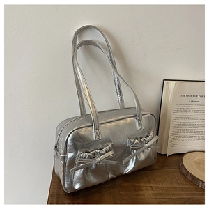 Close-up of silver tote bag showing pleated synthetic leather texture and bow detail