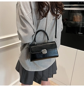 Détail du sac à bandoulière vintage noir avec texture cuir et boucle argentée polie