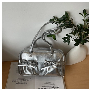 Close-up of silver tote bag with metallic bow details and twin front pockets