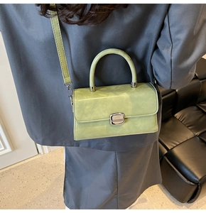 Vue détaillée d'un petit sac bandoulière vert clair porté sur un manteau gris foncé