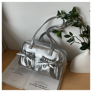 Detail of silver pleated tote bag featuring decorative bows and metallic crinkle texture
