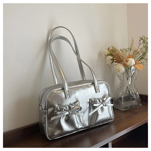Detail view of silver metallic tote bag featuring pleats and decorative bow accents