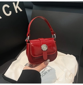 Detail of a red patent leather mini crossbody bag with a silver C-logo buckle