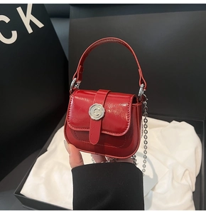 Close-up of a red mini square bag with glossy finish and silver chain strap details