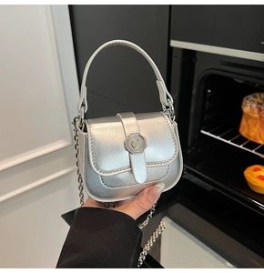 Detailed view of mini silver saddle bag with metallic finish and chic C-logo emblem