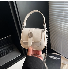 Detail of cream mini square bag with silver C-logo buckle and chain strap being held