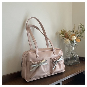 Close-up of leather boston bag featuring silver bow buckles and pleated front pockets