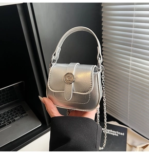 Detail of mini silver metallic chain bag with C-letter clasp and leather texture