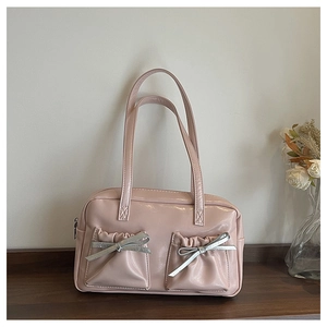 Close-up of pink faux leather tote bag with silver bow details and pleated front pockets