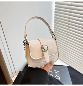 Detail of cream mini square bag featuring silver ring buckle and chain strap