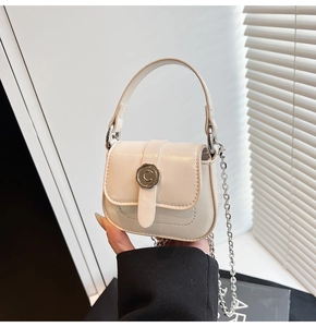 Detailed view of cream mini bag with glossy finish and silver C-shaped turn-lock closure
