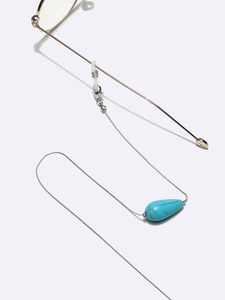 Detail of silver chain eyewear strap featuring a turquoise teardrop bead and silicone loops