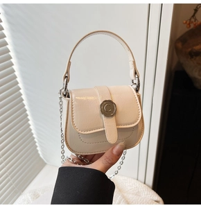 Detail of a creamy white mini square bag with a silver flower lock and chain strap