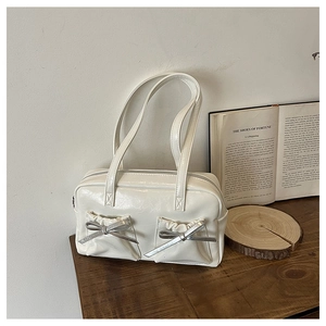 Detail of white leather tote bag featuring functional front pockets and silver bow accents