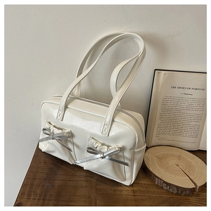 Detail of a beige PU handbag featuring wrinkled texture and two pockets with silver bows