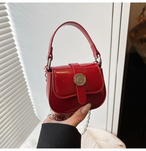 Detail of a red mini leather bag with a C-buckle silver chain and elegant hand-held styling