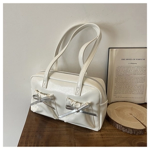 Detailed view of cream white tote bag featuring decorative silver bows and twin pockets