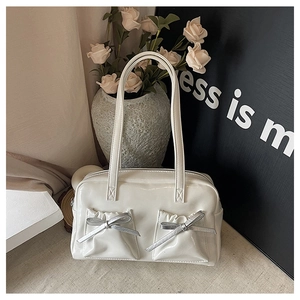 Detail of white patent leather tote bag with silver bows and glossy finish