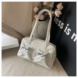 Detail of white tote bag featuring pleated pockets and silver metallic bow accents