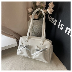 Detail shot of white patent leather tote bag with silver bows and pleated pockets