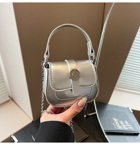 Close-up of a silver mini square bag with metallic texture and C-shaped metal buckle