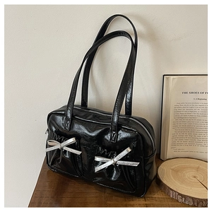 Close-up of black patent leather tote with silver bow pockets and long shoulder straps
