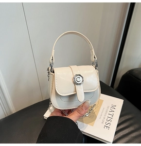 Close-up of off-white mini crossbody bag with silver C-shaped floral metal clasp