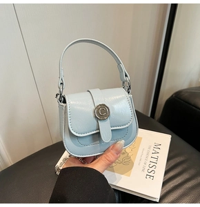 Detail of light blue mini saddle bag with silver buckle and metal chain strap