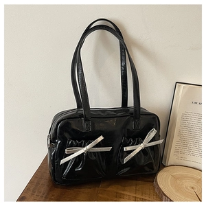Detailed view of the shiny black tote bag with two pleated pockets and silver bows