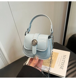 Detail of light blue mini leather crossbody bag with silver buckle and chain strap