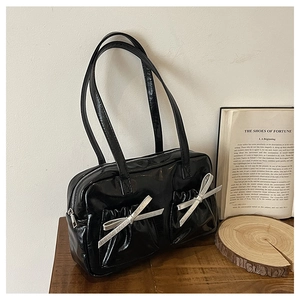 Detail shot of black patent leather tote bag with silver metallic bows and side pockets