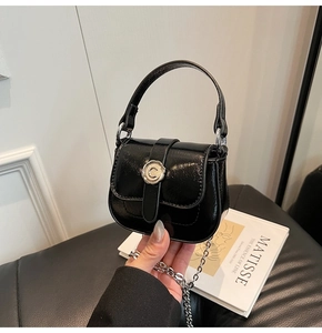 Close-up of black glossy mini bag with C-logo buckle and elegant silver chain strap