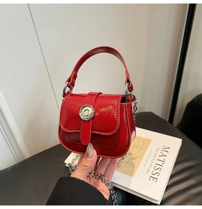 Detail of red patent leather mini square bag with vintage silver buckle and chain strap